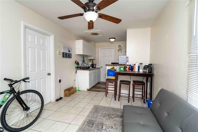 1144AND1142 7th St NW, Largo, FL 33770 - kitchen featuring light tile patterned flooring, white cabinets, dark countertops, a ceiling fan, and a textured wall