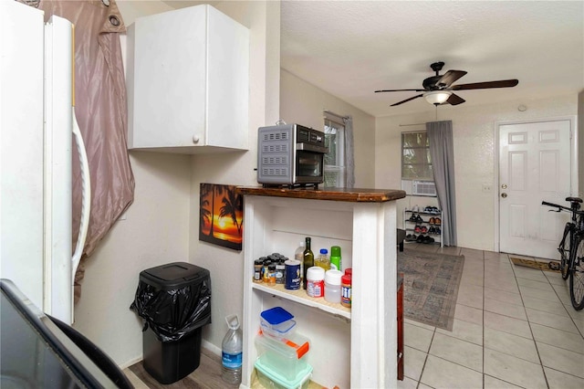 1144AND1142 7th St NW, Largo, FL 33770 - kitchen with white cabinets, refrigerator, a ceiling fan, dark countertops, and light tile patterned floors