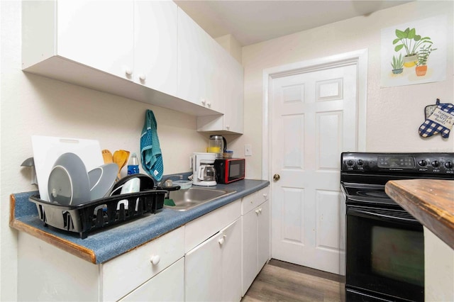 1144AND1142 7th St NW, Largo, FL 33770 - kitchen with black appliances, white cabinets, wood finished floors, and dark countertops