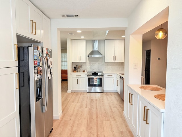 1972 Briarwood St, Dunedin, FL 34698 - kitchen with stainless steel appliances, wall chimney range hood, light wood finished floors, decorative backsplash, and white cabinetry