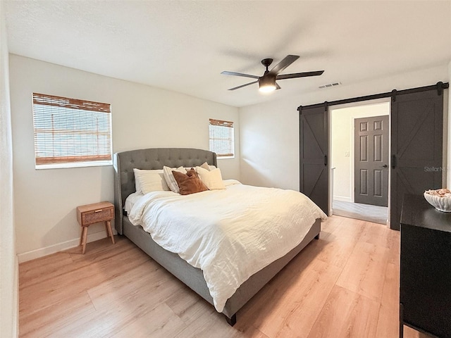 1972 Briarwood St, Dunedin, FL 34698 - bedroom with a barn door, light wood-style flooring, and a ceiling fan