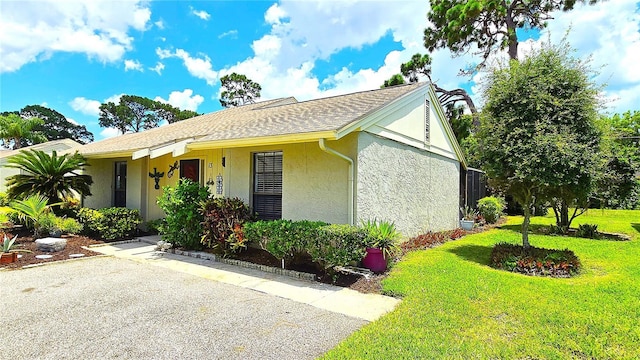 13 Windrush Bay Dr, Tarpon Springs, FL 34689 - view of home's exterior with stucco siding, a lawn, and a shingled roof