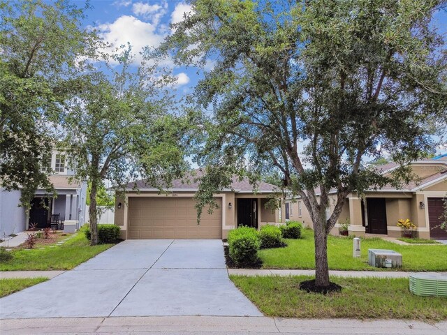 8020 Carriage Pointe Dr, Gibsonton, FL 33534 - view of property hidden behind natural elements with stucco siding, a garage, a front yard, and driveway