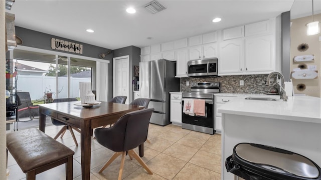 7120 Forest Mere Dr, Riverview, FL 33578 - kitchen featuring appliances with stainless steel finishes, white cabinets, light countertops, decorative backsplash, and light tile patterned flooring