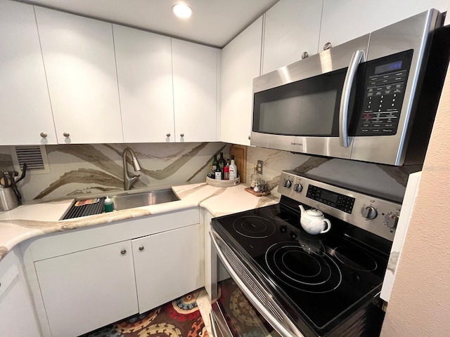 880 Mandalay Ave Unit N311, Clearwater Beach, FL 33767 - kitchen with stainless steel appliances, light countertops, white cabinets, and tasteful backsplash