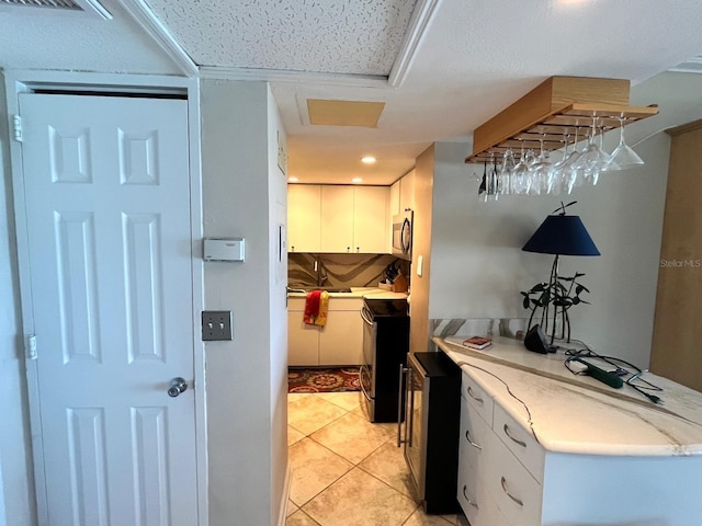 880 Mandalay Ave Unit N311, Clearwater Beach, FL 33767 - kitchen with stainless steel microwave, white cabinets, light tile patterned floors, and light stone counters
