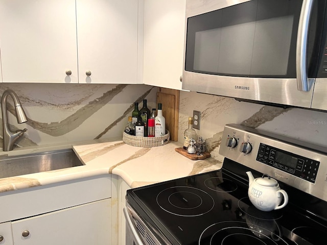 880 Mandalay Ave Unit N311, Clearwater Beach, FL 33767 - kitchen featuring appliances with stainless steel finishes, backsplash, white cabinets, and light countertops
