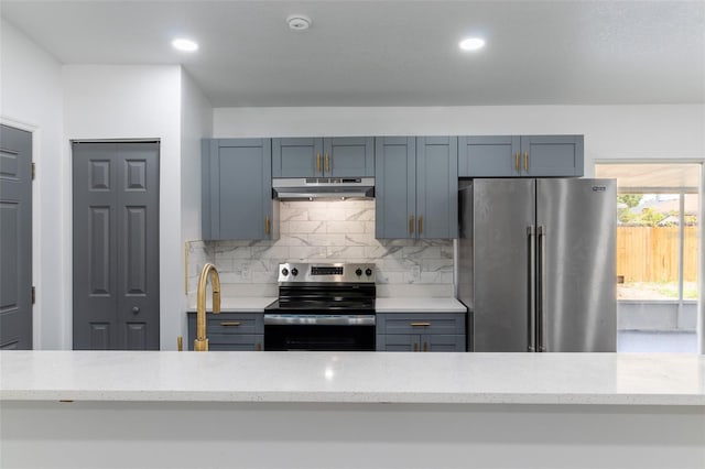 22716 Penny Loop, Land O Lakes, FL 34639 - kitchen featuring appliances with stainless steel finishes, under cabinet range hood, light stone countertops, tasteful backsplash, and recessed lighting