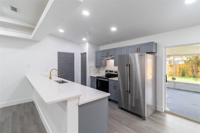 22716 Penny Loop, Land O Lakes, FL 34639 - kitchen with stainless steel appliances, under cabinet range hood, a peninsula, light countertops, and decorative backsplash