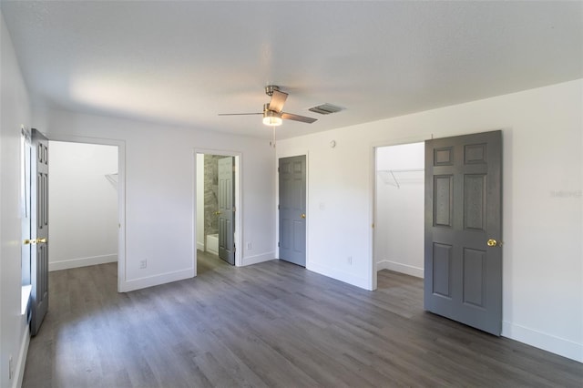 22716 Penny Loop, Land O Lakes, FL 34639 - unfurnished bedroom featuring a walk in closet, a closet, and dark wood-style flooring