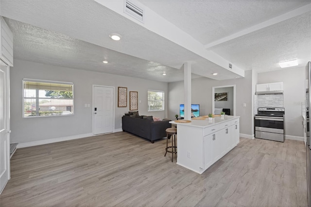 1048 W Lime St, Lakeland, FL 33815 - kitchen with stainless steel electric range, a textured ceiling, open floor plan, white cabinetry, and light wood-type flooring