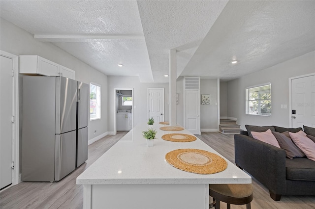 1048 W Lime St, Lakeland, FL 33815 - kitchen with freestanding refrigerator, a textured ceiling, light wood-style floors, open floor plan, and white cabinets