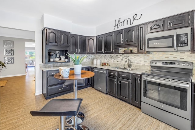 610 Cordova Blvd NE, Saint Petersburg, FL 33704 - kitchen with stainless steel appliances, decorative backsplash, light wood-style floors, and light stone countertops