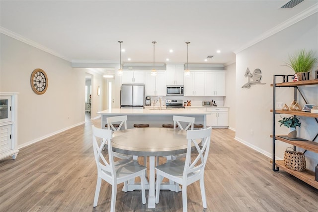 6879 Talamore Dr, Wesley Chapel, FL 33545 - dining room with ornamental molding, light wood finished floors, and recessed lighting