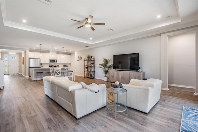 6879 Talamore Dr, Wesley Chapel, FL 33545 - living area featuring a raised ceiling, ceiling fan, light wood-style flooring, crown molding, and recessed lighting