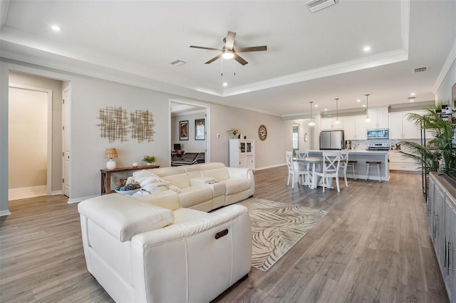 6879 Talamore Dr, Wesley Chapel, FL 33545 - living area with a tray ceiling, ceiling fan, light wood-type flooring, crown molding, and recessed lighting