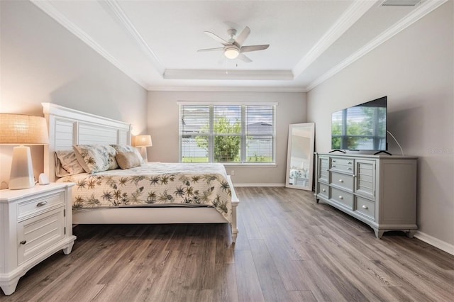 6879 Talamore Dr, Wesley Chapel, FL 33545 - bedroom featuring wood finished floors, a tray ceiling, ornamental molding, and a ceiling fan
