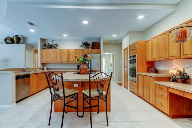 1827 Foxboro Ct, Oldsmar, FL 34677 - kitchen with appliances with stainless steel finishes, a breakfast bar area, light countertops, a center island, and light tile patterned floors