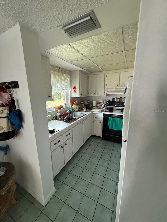 102 47th Avenue Dr W Unit 136, Bradenton, FL 34207 - kitchen with range with electric stovetop, under cabinet range hood, light tile patterned floors, white cabinets, and light countertops