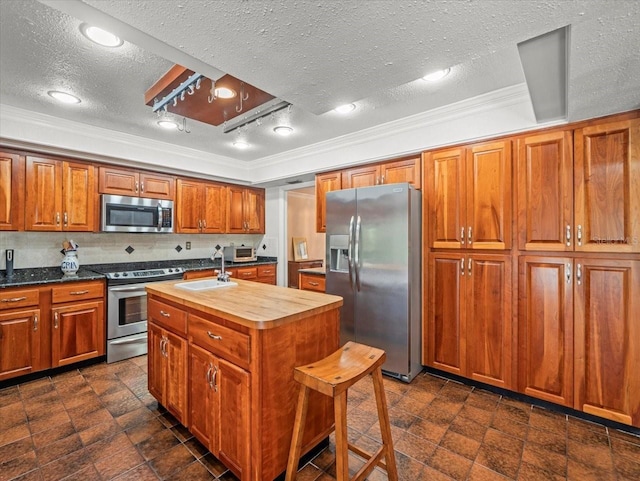 4118 Carrollwood Village Dr, Tampa, FL 33618 - kitchen with appliances with stainless steel finishes, wood counters, crown molding, a textured ceiling, and a center island with sink