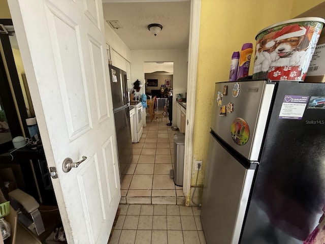 7206 Reindeer Rd, Tampa, FL 33619 - kitchen with freestanding refrigerator, light tile patterned floors, and white cabinetry