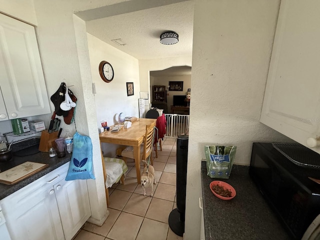 7206 Reindeer Rd, Tampa, FL 33619 - kitchen with white cabinets, dark countertops, light tile patterned floors, and a textured ceiling