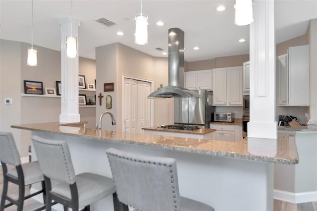 6513 Sand Shore Ln, New Port Richey, FL 34652 - kitchen with island exhaust hood, ornate columns, black oven, white cabinetry, and freestanding refrigerator