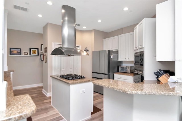 6513 Sand Shore Ln, New Port Richey, FL 34652 - kitchen with island exhaust hood, black appliances, white cabinets, light wood-style floors, and a peninsula
