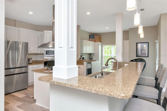6513 Sand Shore Ln, New Port Richey, FL 34652 - kitchen featuring appliances with stainless steel finishes, light wood-style floors, a kitchen breakfast bar, white cabinetry, and decorative light fixtures