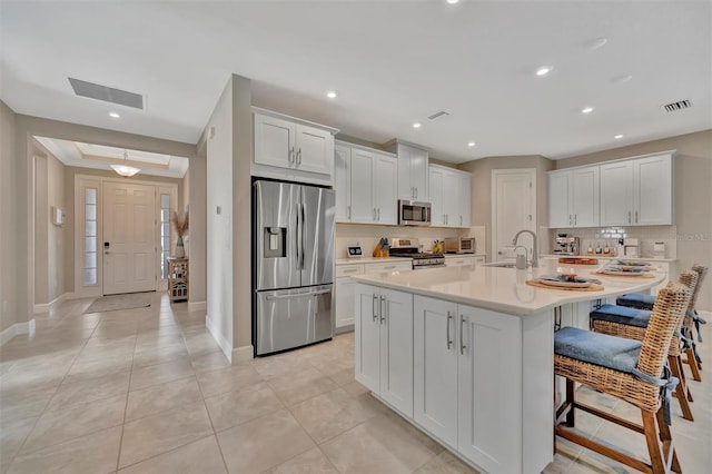 5320 Morey Farms Loop, Palmetto, FL 34221 - kitchen with appliances with stainless steel finishes, tasteful backsplash, light countertops, a kitchen bar, and white cabinetry
