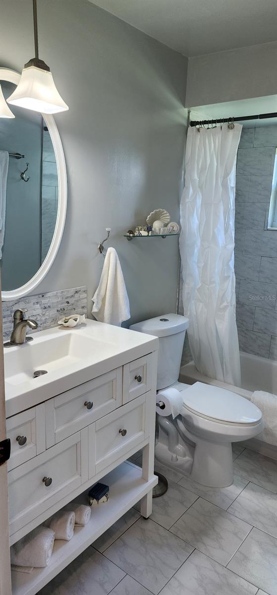 1583 Eunice Ln, Clearwater, FL 33756 - full bathroom with vanity, shower / tub combo, marble look tiles, and backsplash
