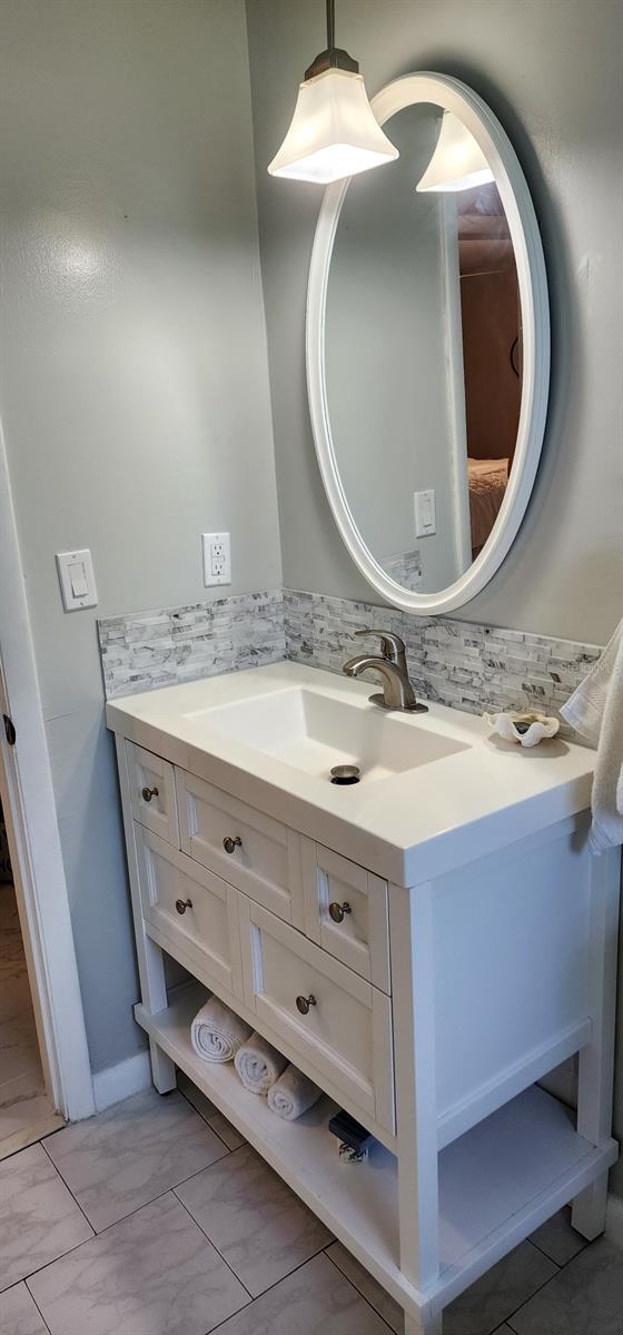 1583 Eunice Ln, Clearwater, FL 33756 - bathroom with vanity, marble finish floors, and decorative backsplash
