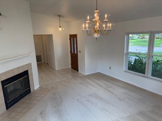 1922 Blue Sage Ct, Brandon, FL 33511 - unfurnished living room featuring a chandelier, light carpet, lofted ceiling, a tile fireplace, and light tile patterned flooring