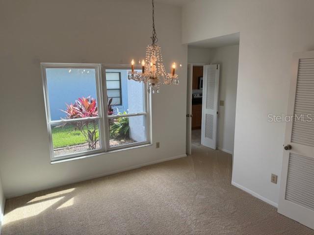 1922 Blue Sage Ct, Brandon, FL 33511 - unfurnished dining area with a chandelier, carpet flooring, and a towering ceiling