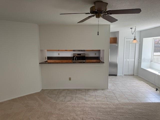 1922 Blue Sage Ct, Brandon, FL 33511 - kitchen with freestanding refrigerator, dark countertops, a ceiling fan, stove, and pendant lighting