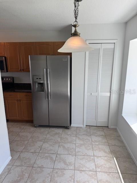 1922 Blue Sage Ct, Brandon, FL 33511 - kitchen with appliances with stainless steel finishes, brown cabinetry, pendant lighting, and light tile patterned floors