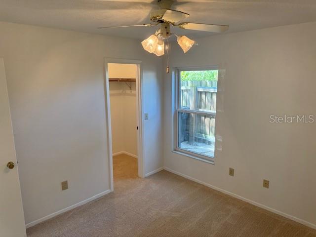 1922 Blue Sage Ct, Brandon, FL 33511 - unfurnished bedroom with a walk in closet, light colored carpet, a closet, and a ceiling fan
