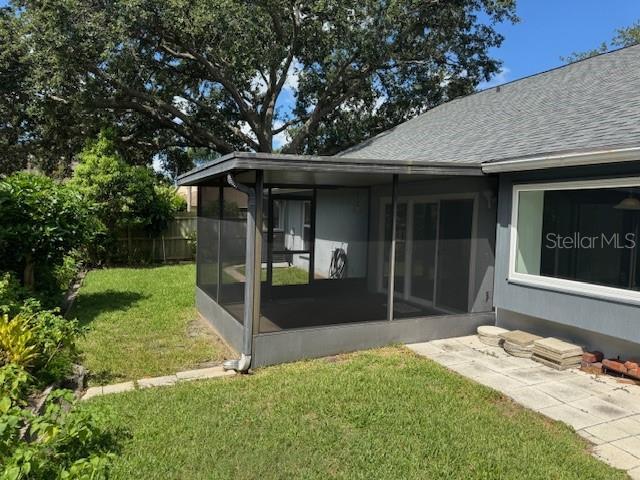 1922 Blue Sage Ct, Brandon, FL 33511 - rear view of property with a sunroom, a shingled roof, and a yard