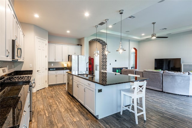 6817 Ebb Tide Ave, Apollo Beach, FL 33572 - kitchen with arched walkways, appliances with stainless steel finishes, tasteful backsplash, dark wood-type flooring, and a center island with sink