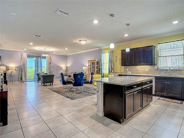 11703 Brighton Knoll Loop, Riverview, FL 33579 - kitchen featuring light tile patterned flooring, light stone countertops, decorative backsplash, a textured ceiling, and hanging light fixtures