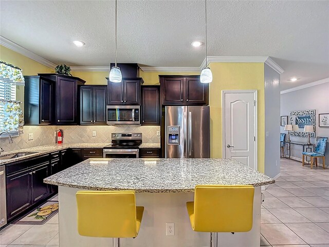 11703 Brighton Knoll Loop, Riverview, FL 33579 - kitchen featuring appliances with stainless steel finishes, a center island, light stone countertops, crown molding, and backsplash