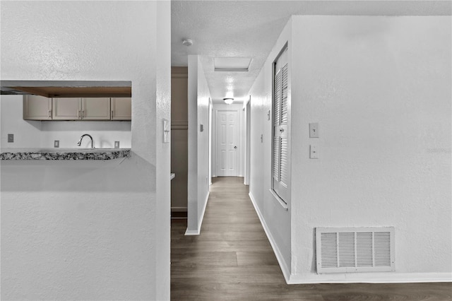 1116 Jadewood Ave, Clearwater, FL 33759 - hall with attic access, wood finished floors, and a textured wall