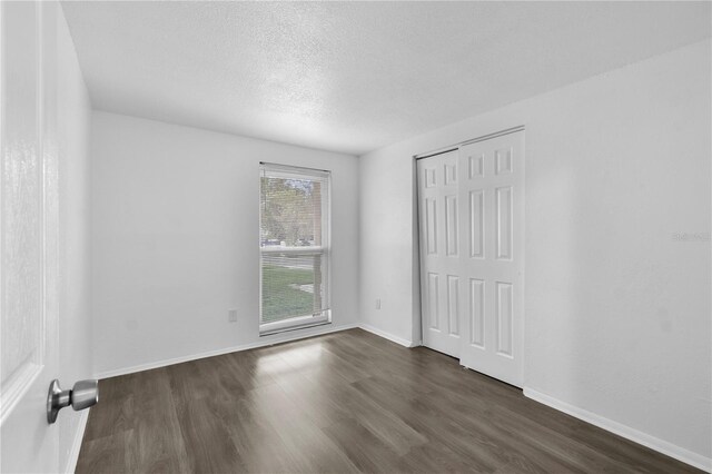 1116 Jadewood Ave, Clearwater, FL 33759 - unfurnished bedroom featuring dark wood-type flooring, a textured ceiling, and a closet