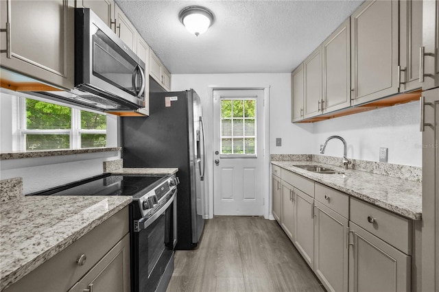1116 Jadewood Ave, Clearwater, FL 33759 - kitchen featuring stainless steel appliances, light wood-style floors, a textured ceiling, light stone counters, and gray cabinets