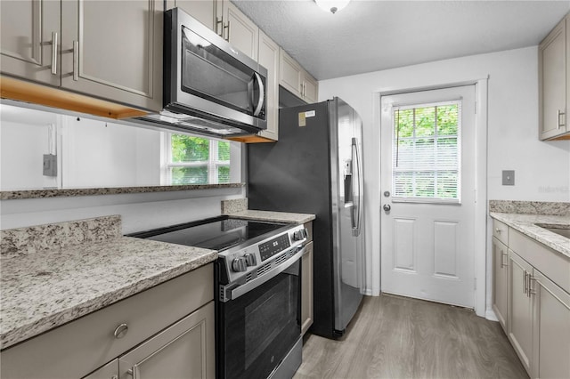 1116 Jadewood Ave, Clearwater, FL 33759 - kitchen featuring appliances with stainless steel finishes, light wood-style floors, light stone counters, and gray cabinetry