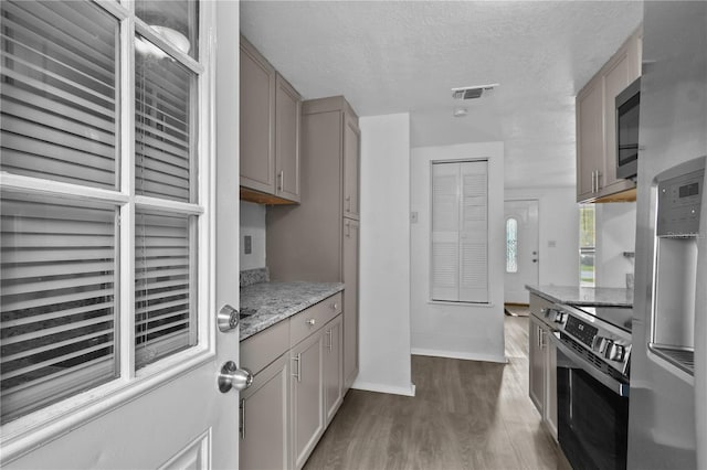 1116 Jadewood Ave, Clearwater, FL 33759 - kitchen with appliances with stainless steel finishes, dark wood finished floors, a textured ceiling, light stone countertops, and gray cabinetry