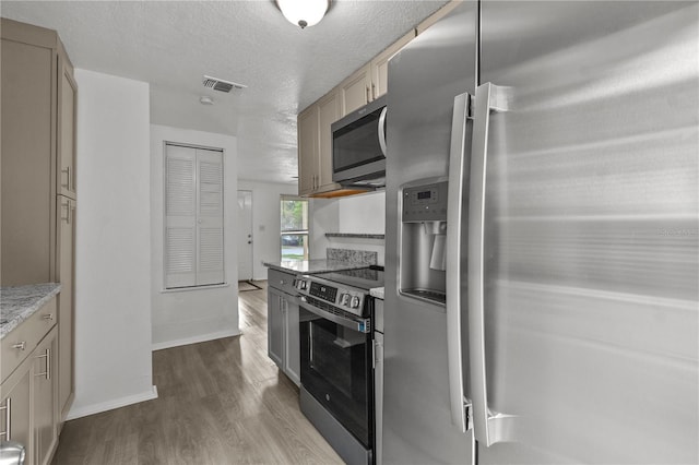 1116 Jadewood Ave, Clearwater, FL 33759 - kitchen with stainless steel appliances, dark wood-style flooring, a textured ceiling, and light stone counters