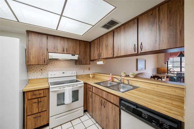 2131 Ridge Rd S Unit 19, Largo, FL 33778 - kitchen with white appliances, under cabinet range hood, light tile patterned flooring, and brown cabinetry
