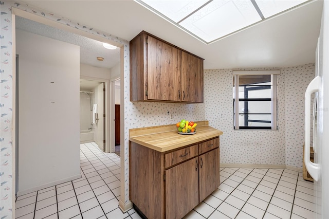 2131 Ridge Rd S Unit 19, Largo, FL 33778 - kitchen featuring wallpapered walls, light tile patterned flooring, butcher block counters, and brown cabinets