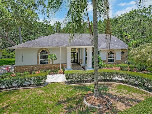 8711 Crescent Forest Blvd, New Port Richey, FL 34654 - view of front of house featuring stucco siding, brick siding, a shingled roof, french doors, and a front yard